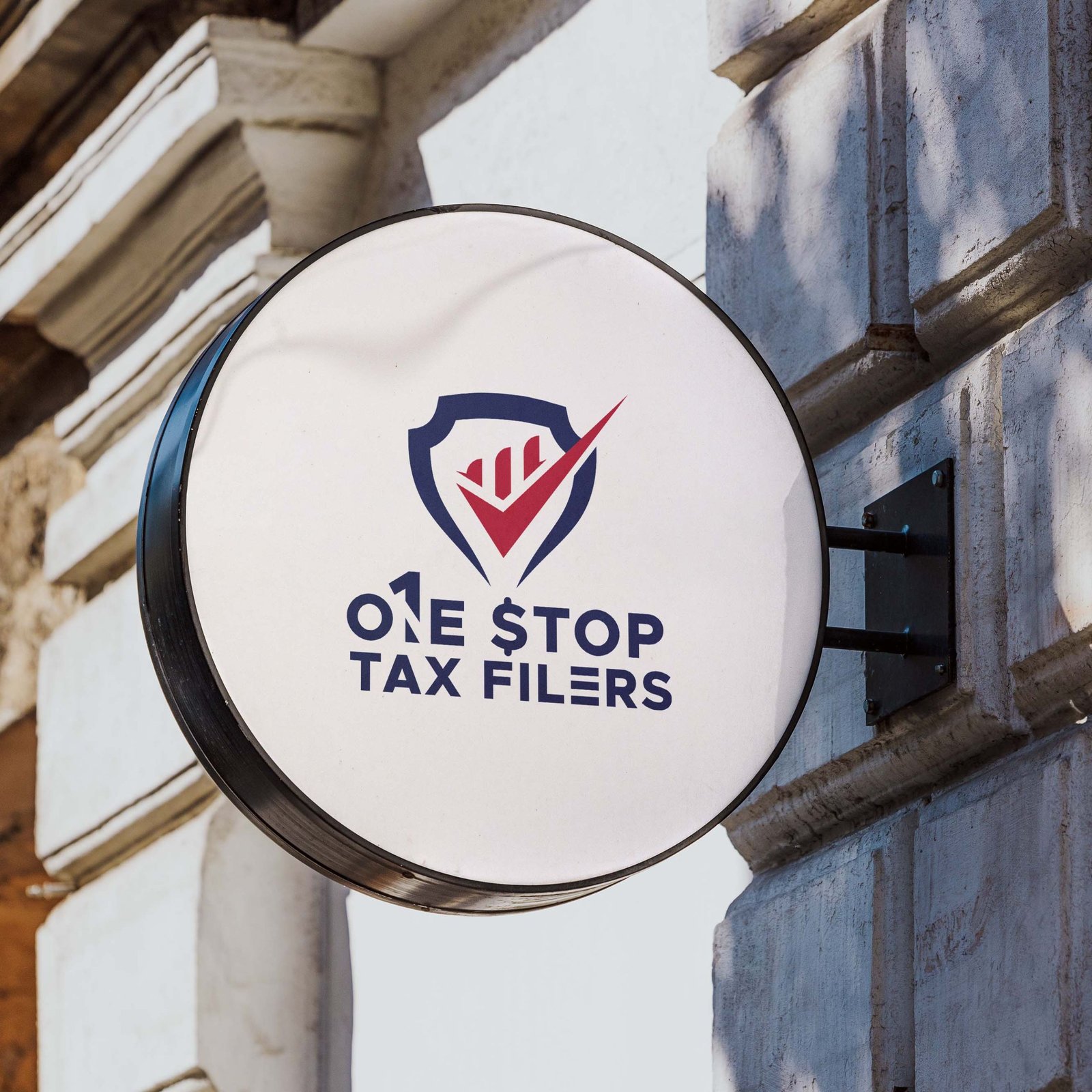 Circular signboard displaying the logo and name of "One Stop Tax Filers," featuring a shield design with a checkmark and bar graph elements.